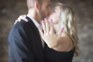 man and woman kissing with woman showing engagement ring on left hand wedding finger.